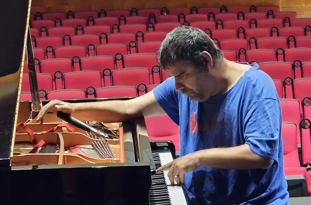 blind piano technician tuning piano at a performance hall