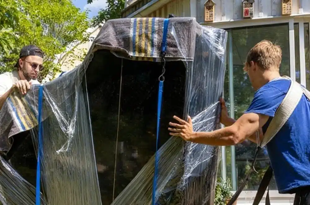 2 guys moving a wrapped piano